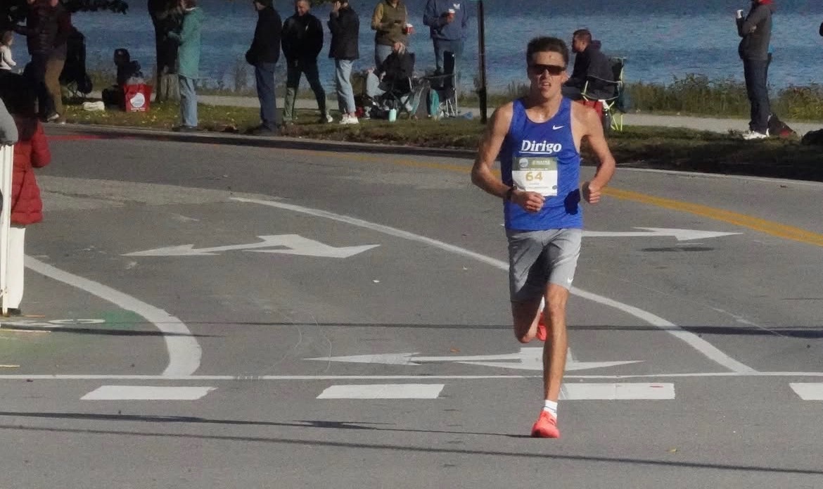 A Dirigo runner in a blue singlet and gray shorts racing beside Back Cove.