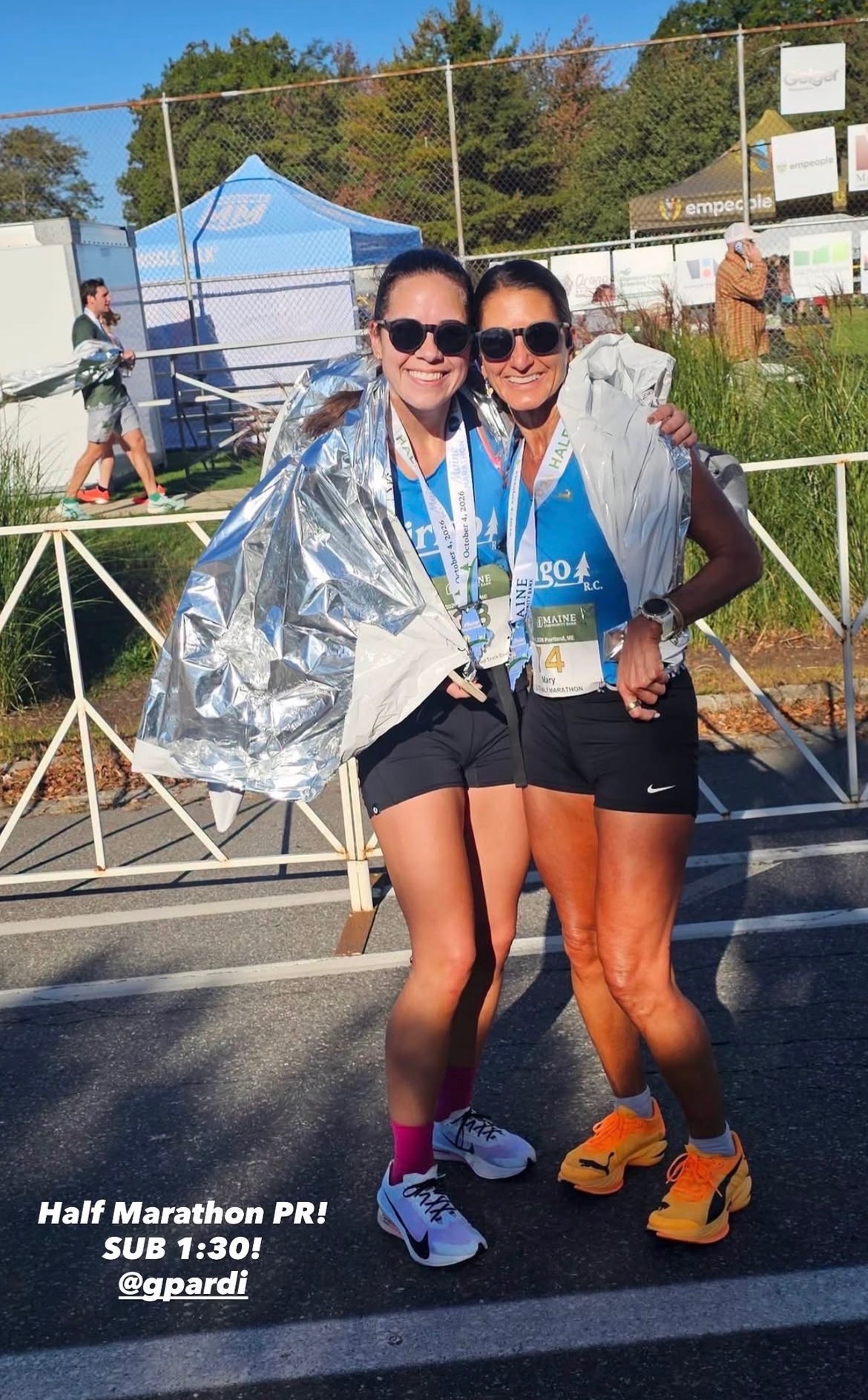 Two Dirigo runners with medals and foil blankets; the photo celebrates a sub-1:30 half marathon PR.
